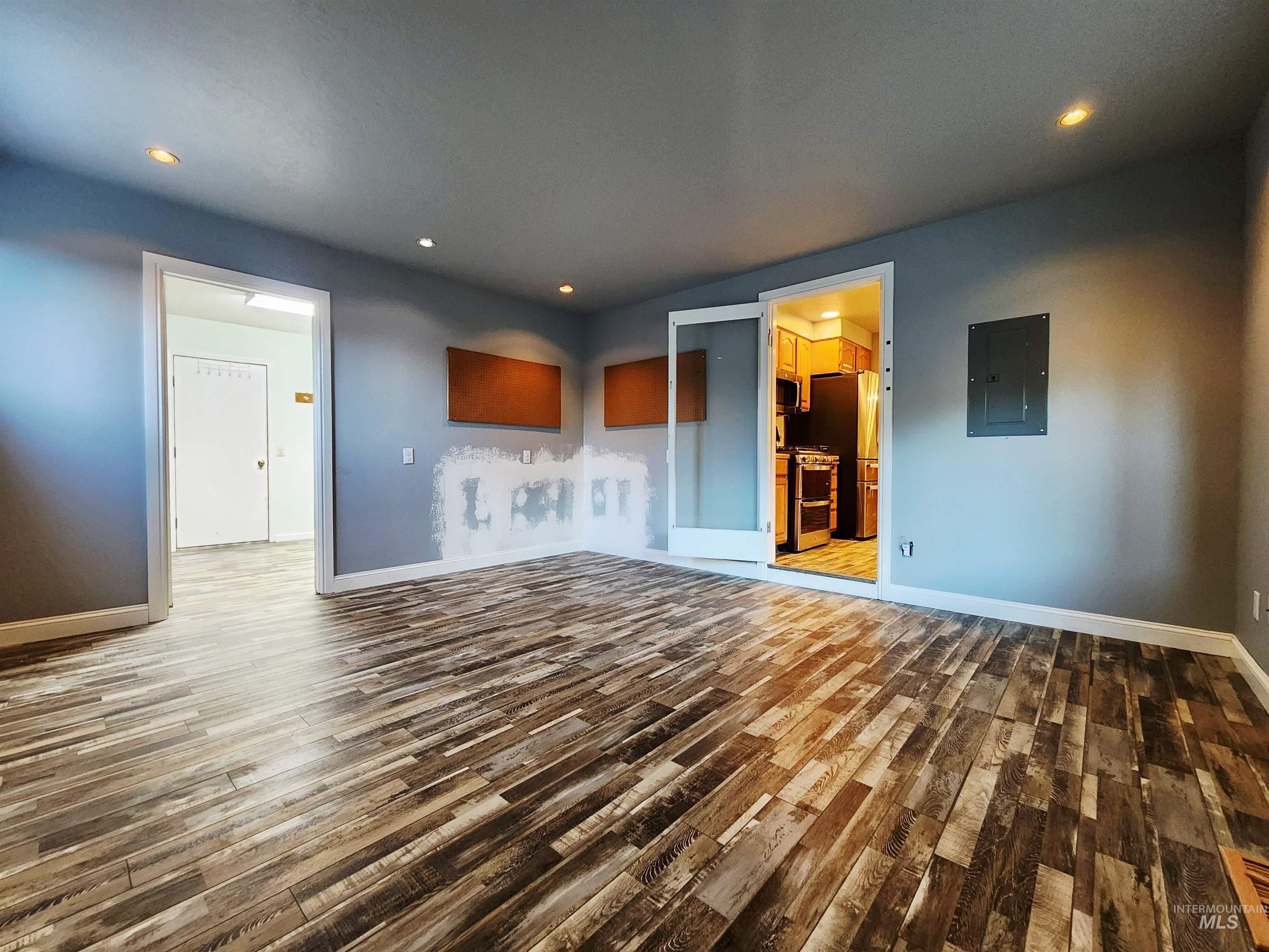 Unfurnished living room with dark wood-style flooring, recessed lighting, and electric panel