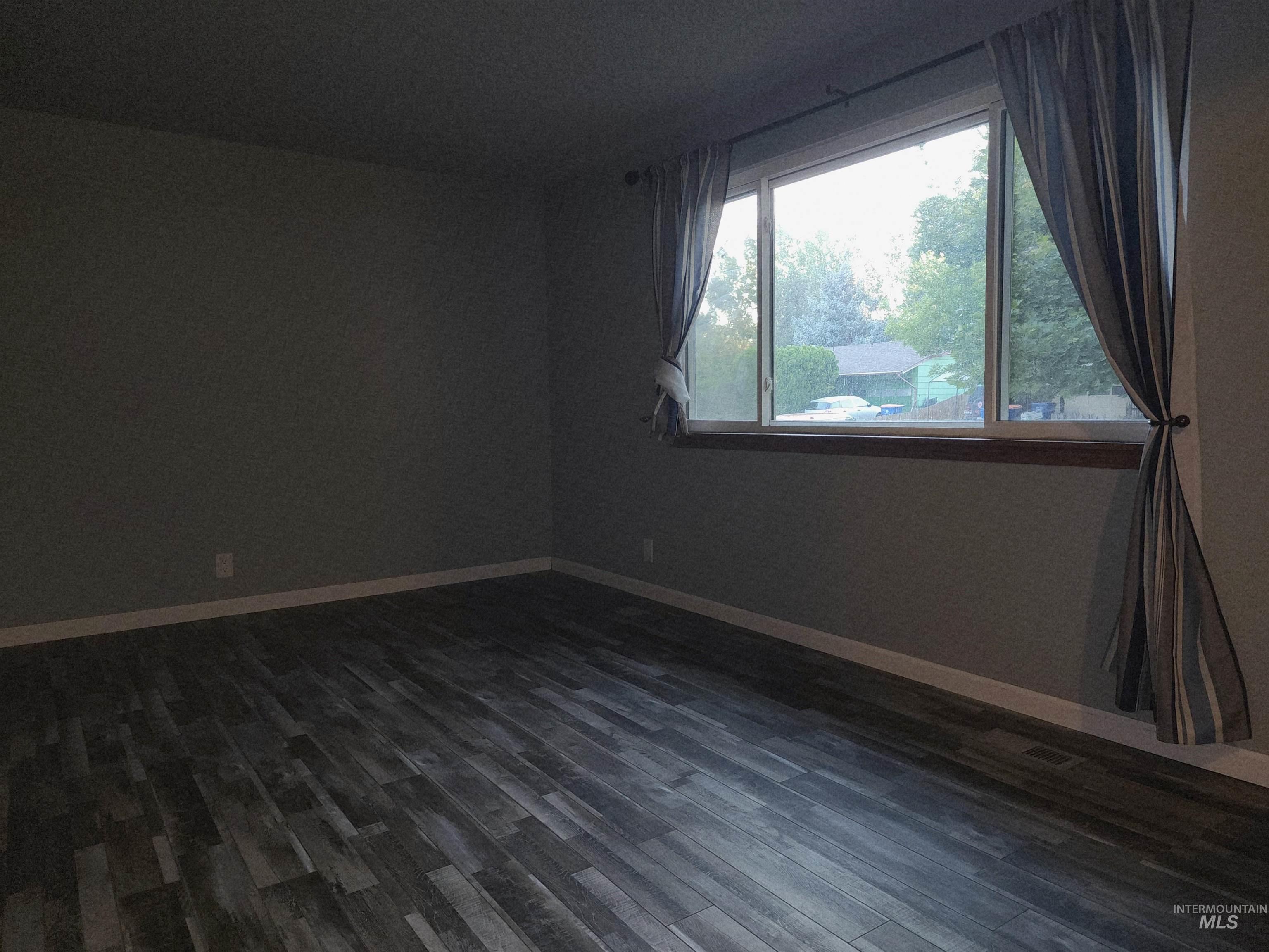 Empty room with dark wood-style flooring and baseboards