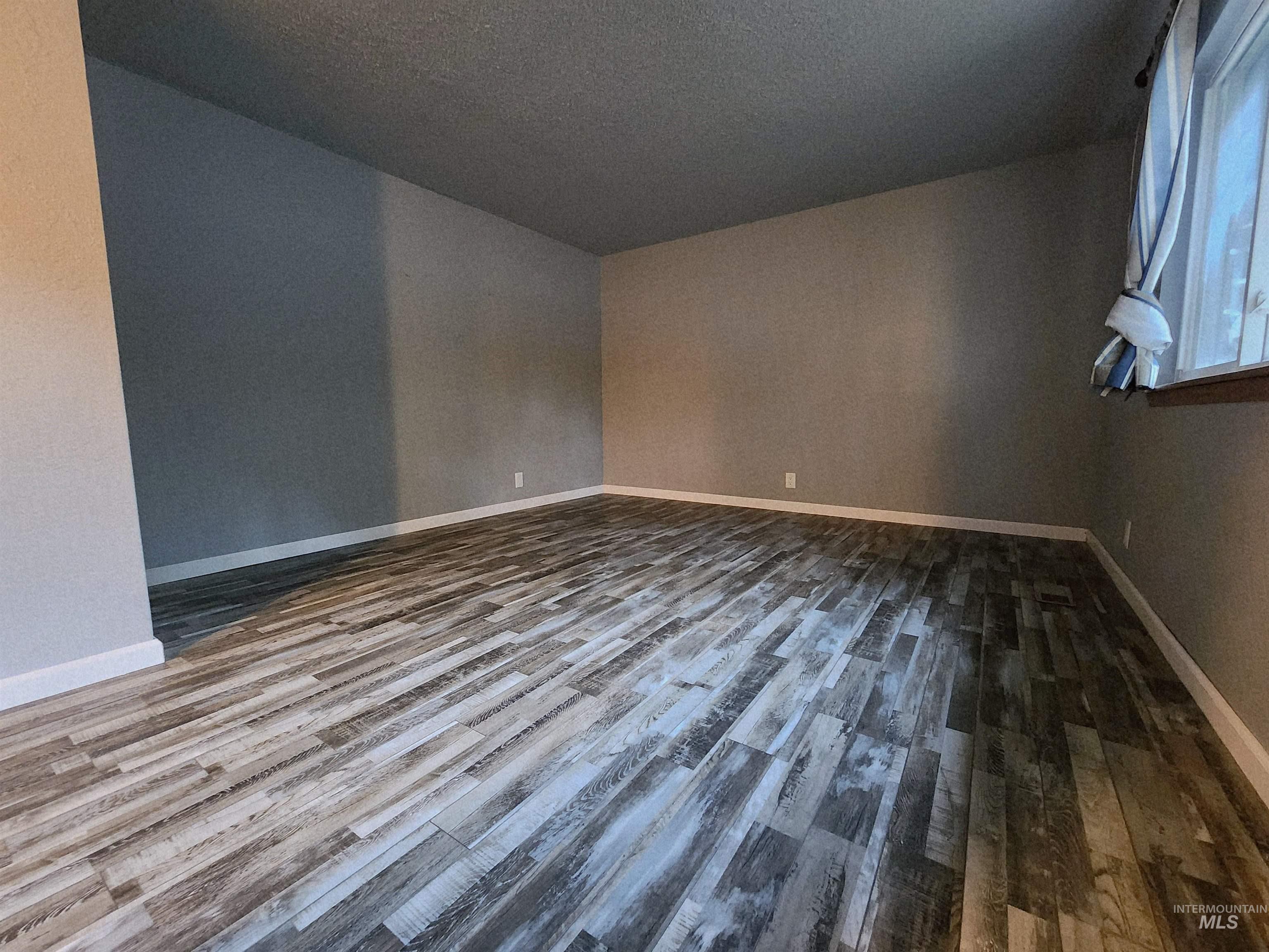 Unfurnished room with dark wood finished floors and baseboards