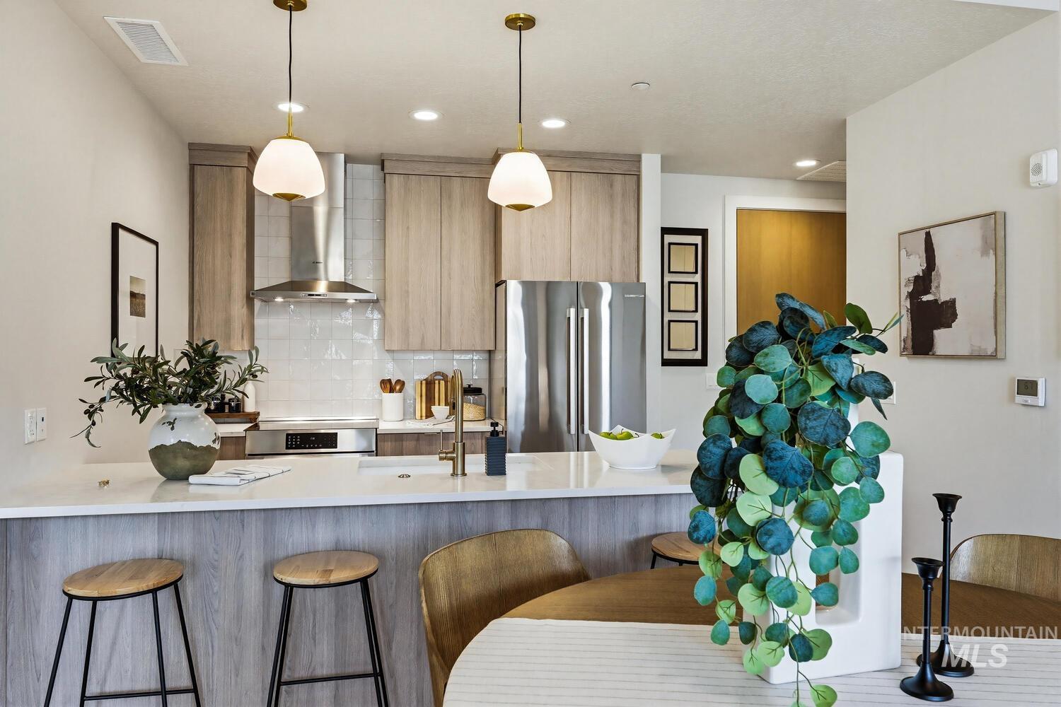 Kitchen with a peninsula, stainless steel appliances, a kitchen breakfast bar, modern cabinets, and light wood finish cabinetry