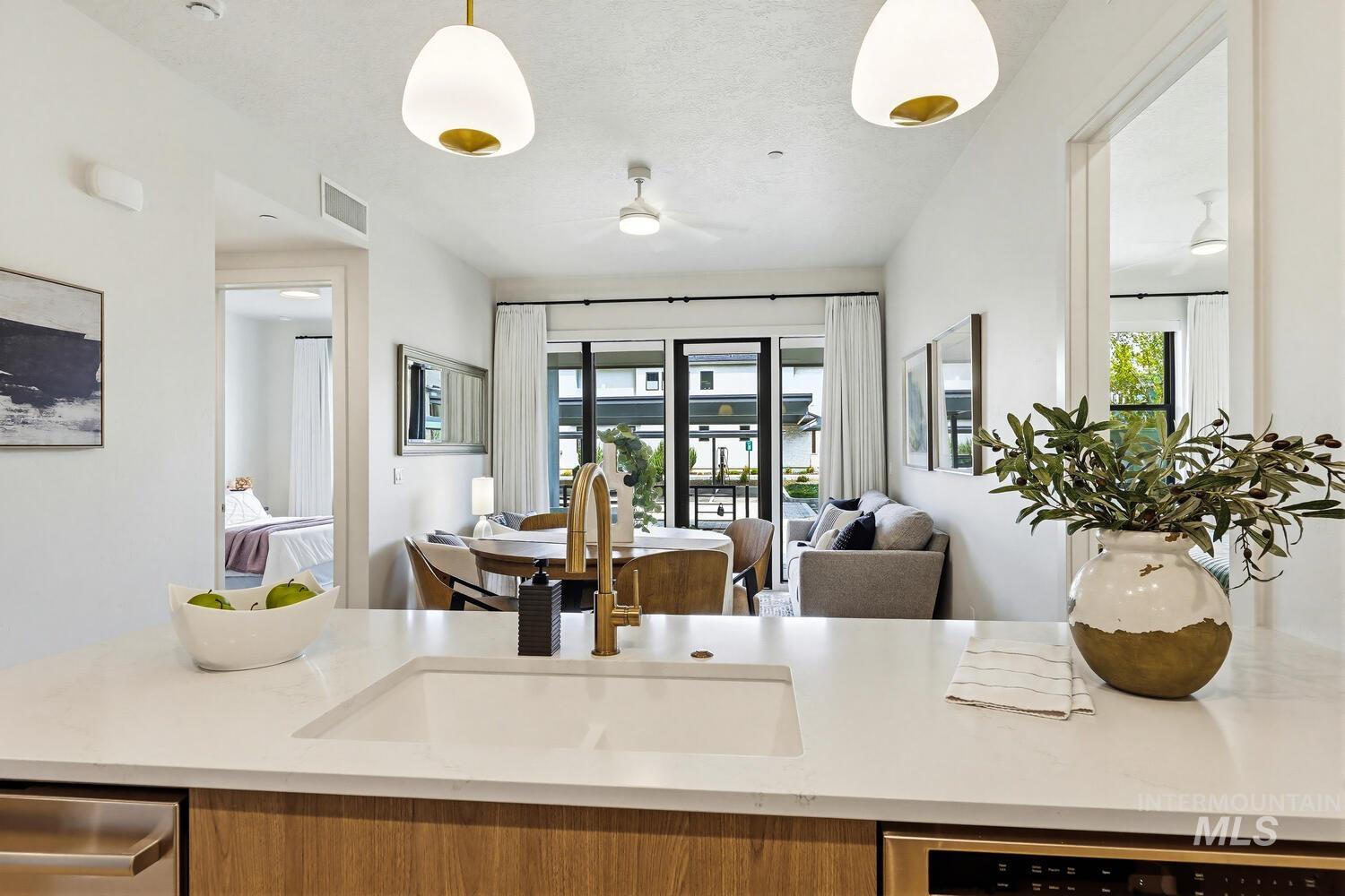 Kitchen with open floor plan, light stone counters, dishwasher, and ceiling fan