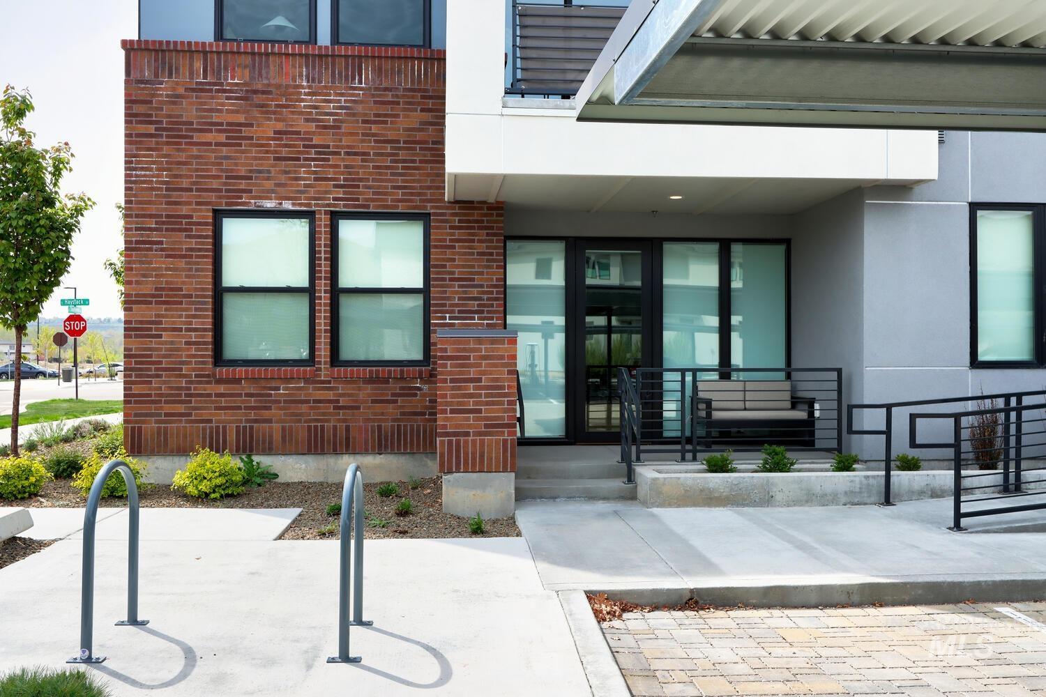 Entrance to property with brick siding, a porch, and stucco siding
