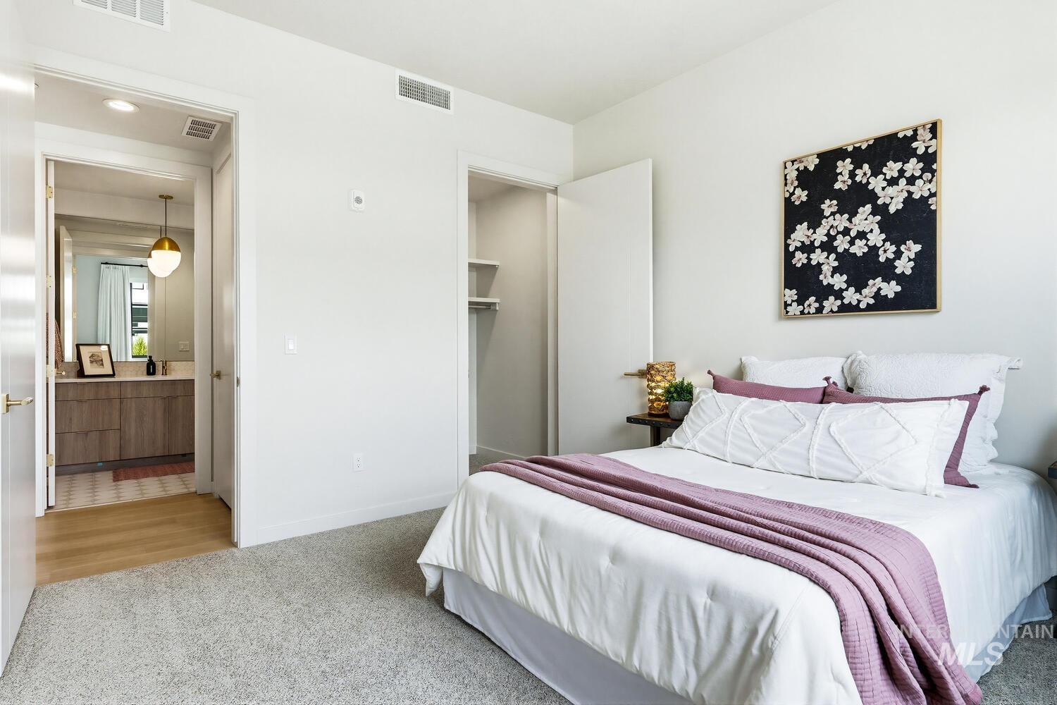 Bedroom featuring light colored carpet and a spacious closet