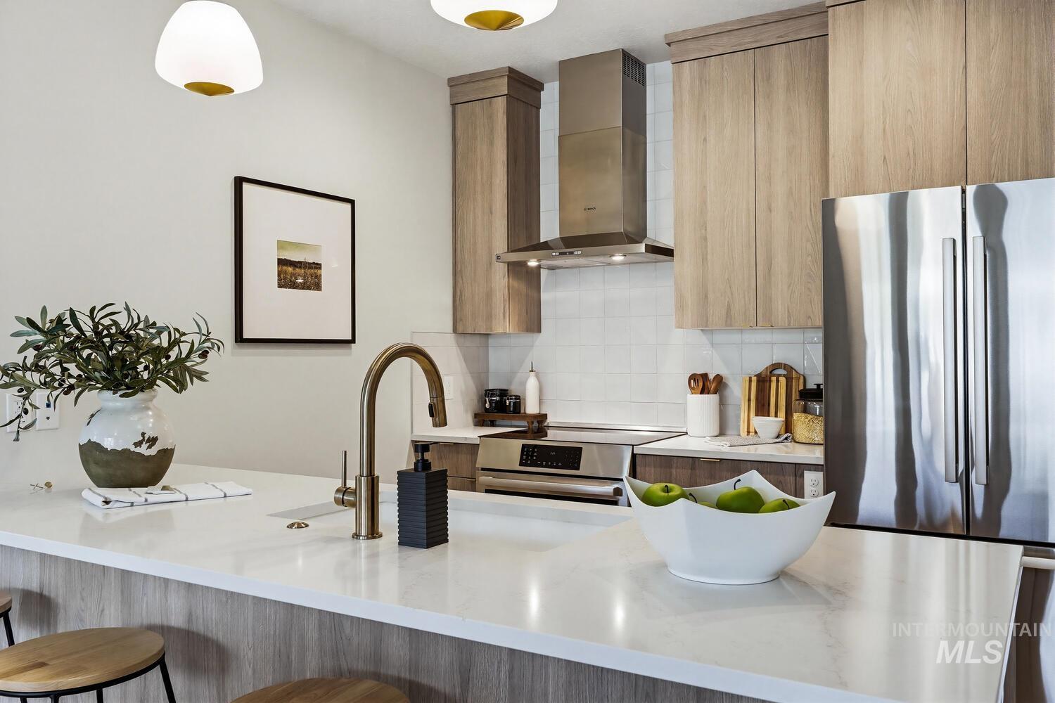 Kitchen with modern cabinets, light stone countertops, stainless steel appliances, and tasteful backsplash
