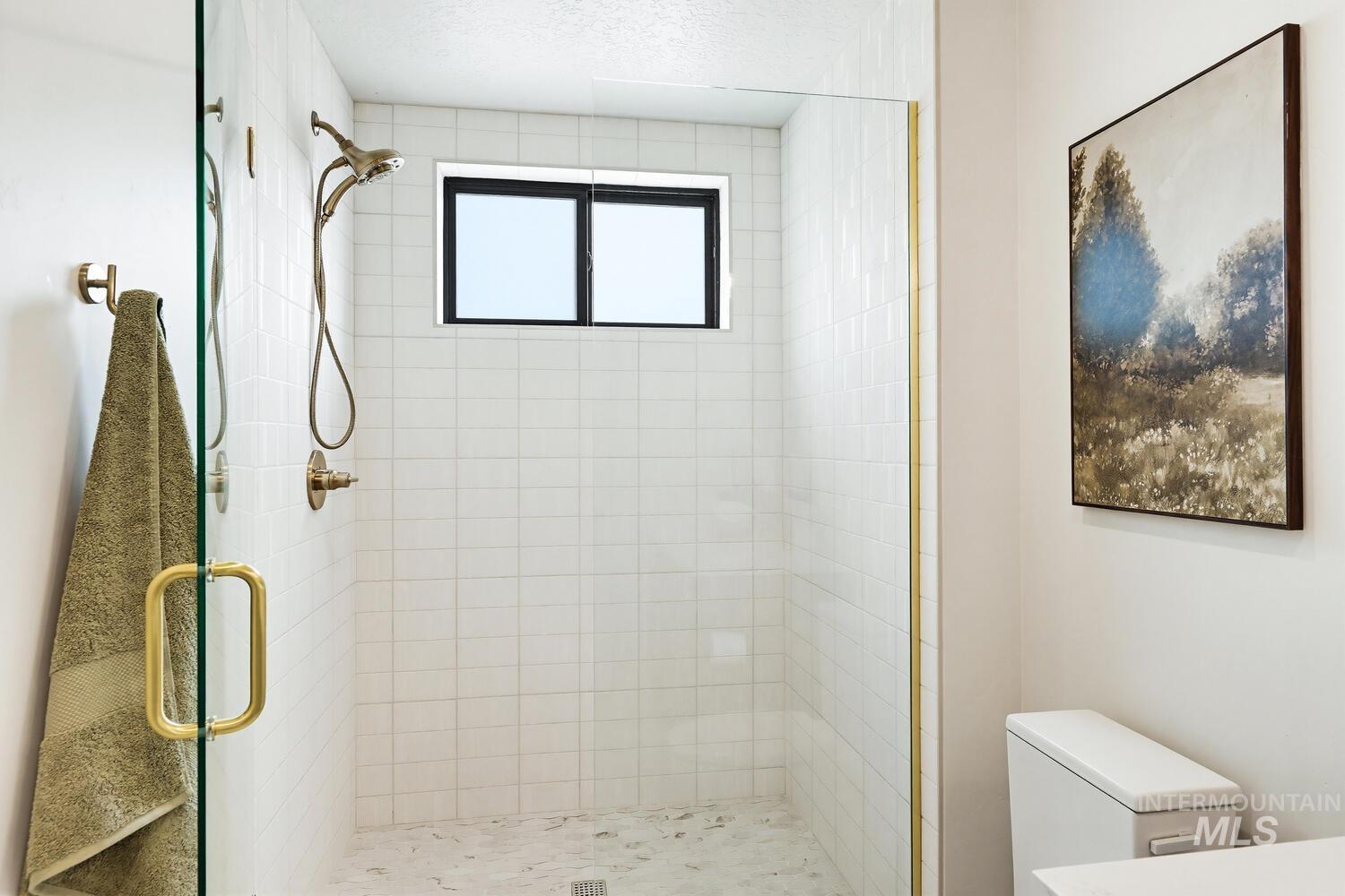 Full bathroom featuring a shower stall and toilet
