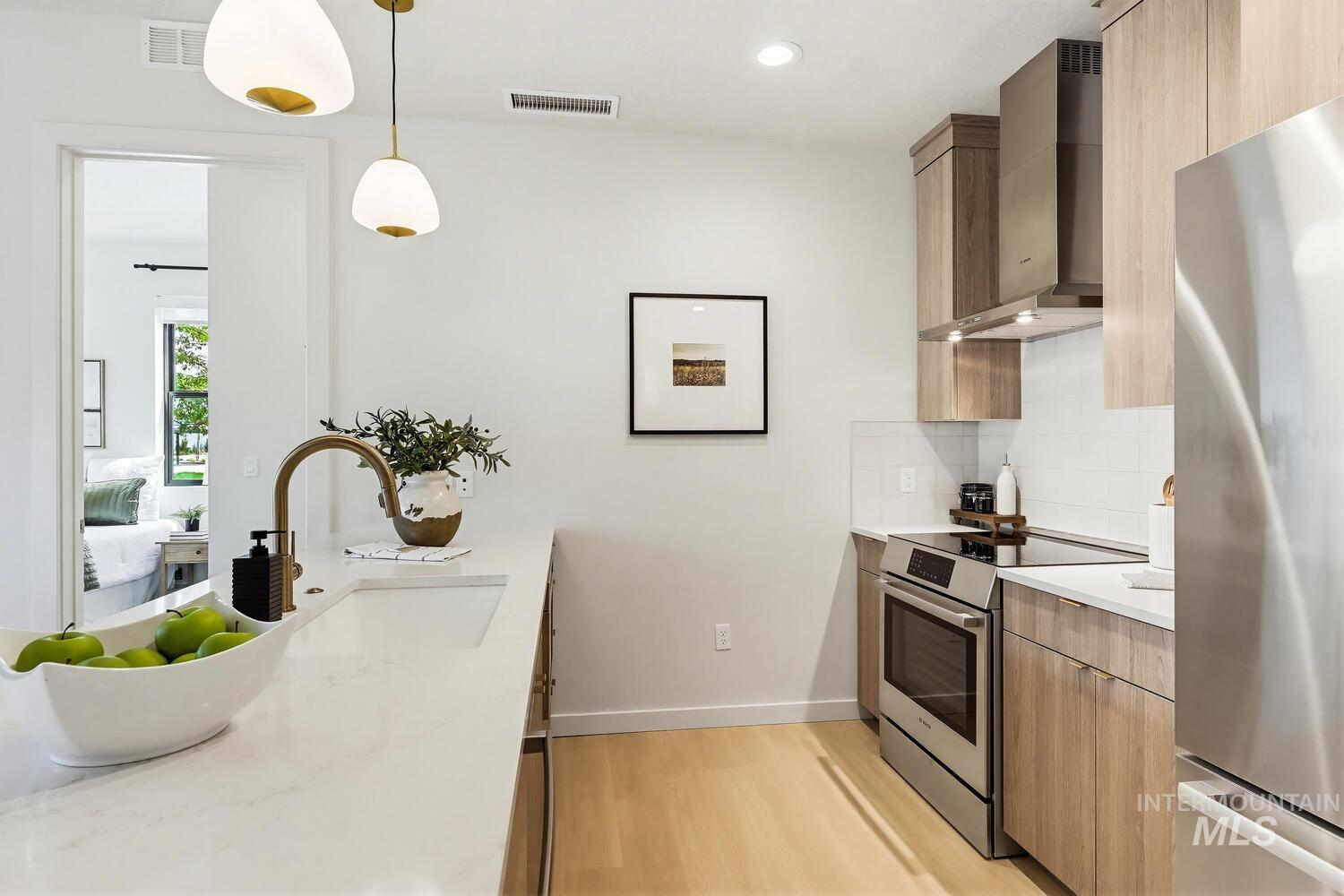 Kitchen featuring stainless steel appliances, light stone counters, modern cabinets, light wood-style floors, and pendant lighting