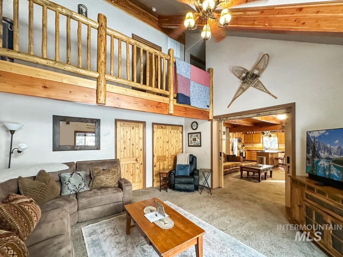 Carpeted living room with high vaulted ceiling and beamed ceiling