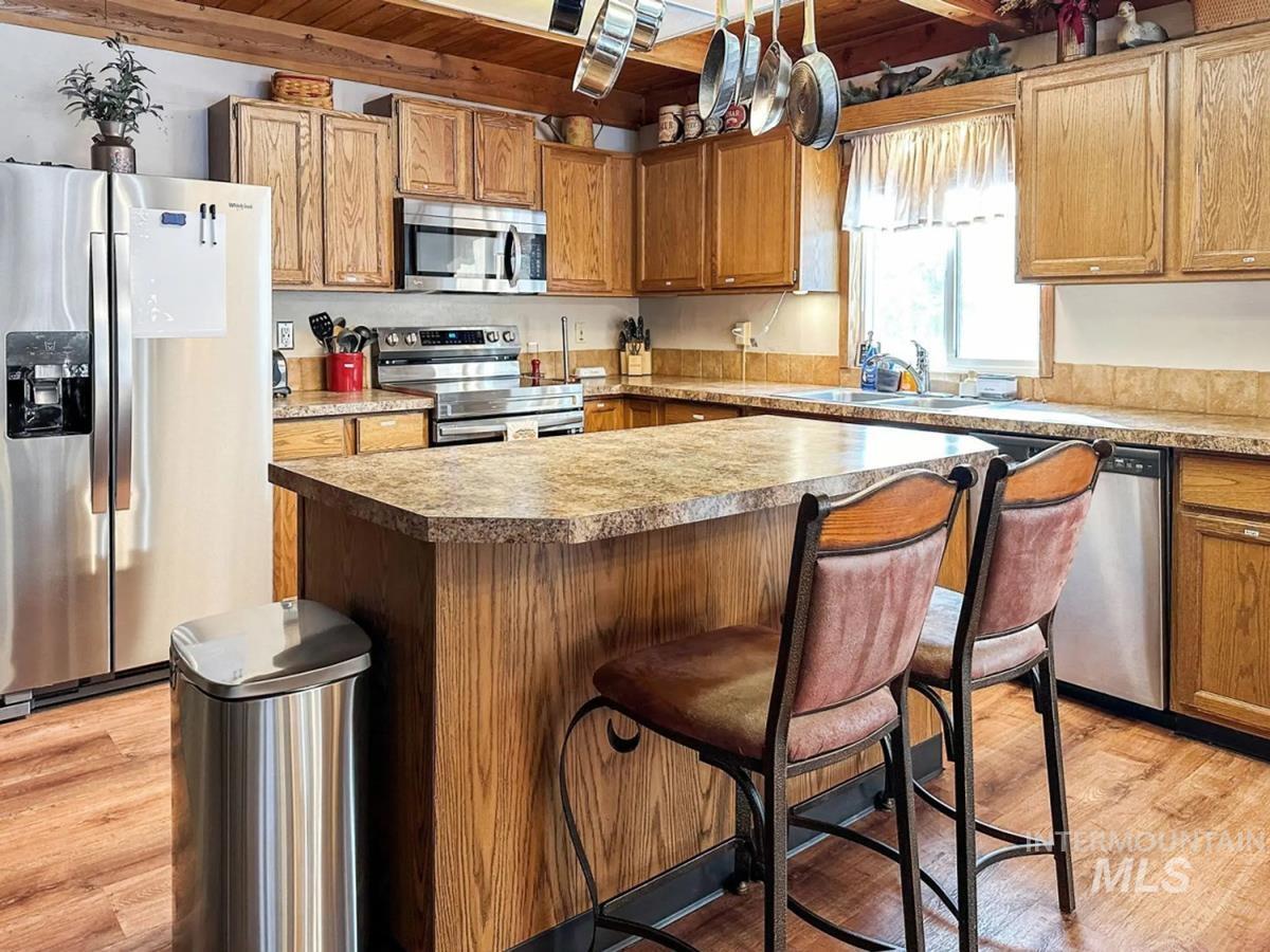 Kitchen featuring appliances with stainless steel finishes, light wood finished floors, a kitchen breakfast bar, a center island, and wood ceiling