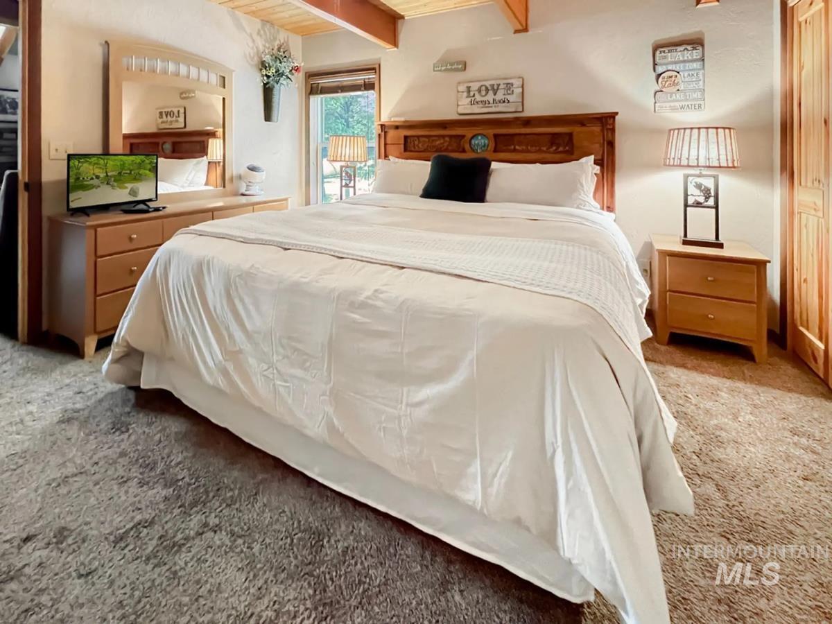 Bedroom featuring light colored carpet, beamed ceiling, and access to exterior