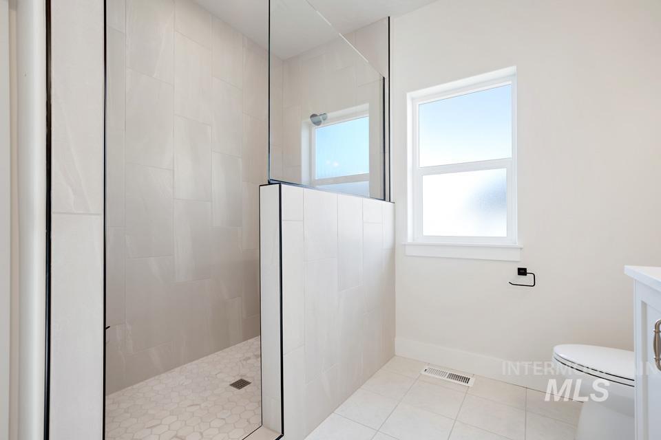 Bathroom featuring vanity, a walk in shower, and light tile patterned floors