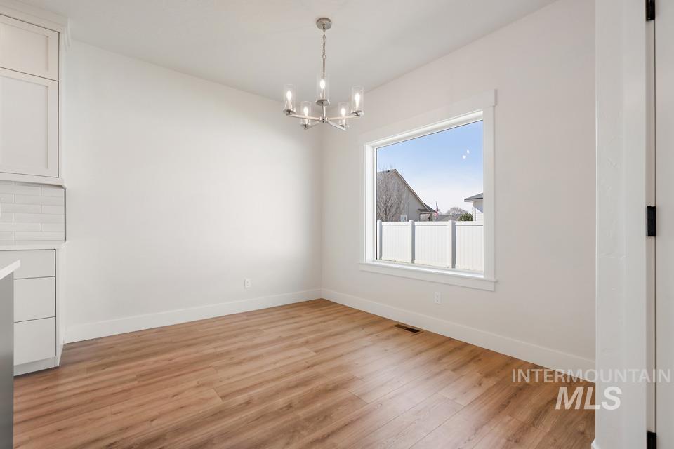 Unfurnished dining area with light wood-style flooring and suspended lighting