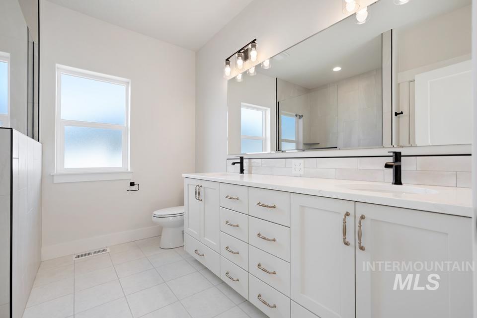 Bathroom with double vanity, light tile patterned floors, and walk in shower