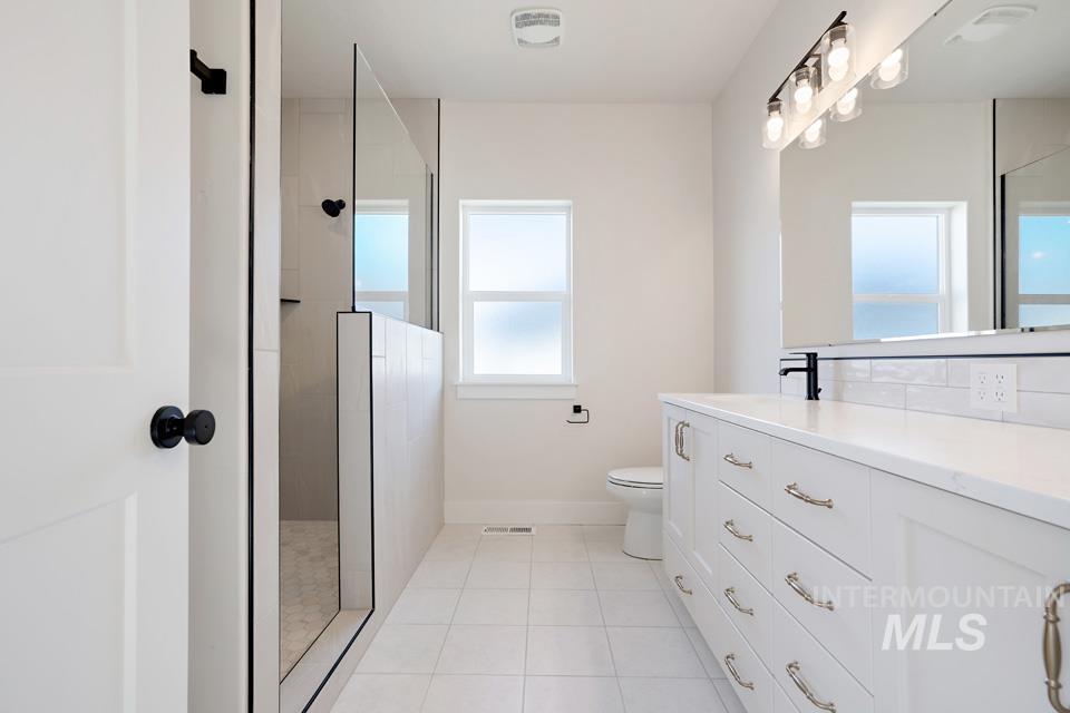 Bathroom featuring walk in shower, vanity, and light tile patterned flooring