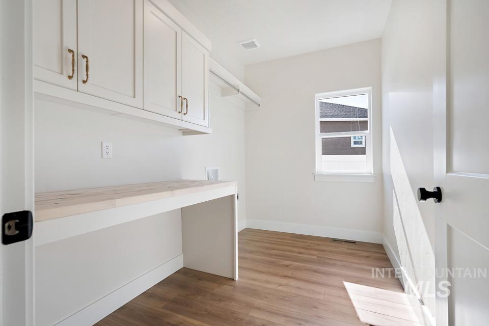 Laundry area featuring light wood-type flooring, washer hookup, and cabinet space