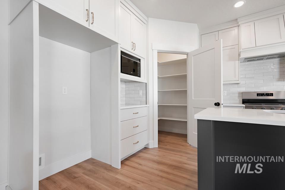 Kitchen featuring decorative backsplash, light wood-style flooring, stainless steel electric range oven, dual tone cabinetry, and recessed lighting