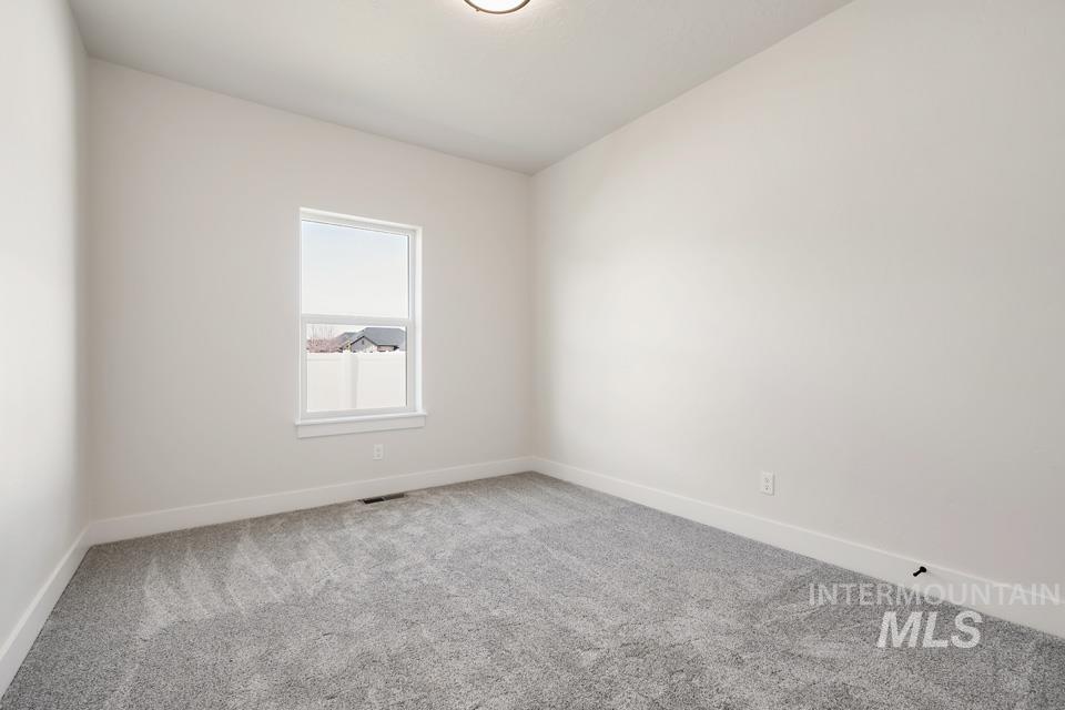 Empty room featuring light colored carpet and baseboards