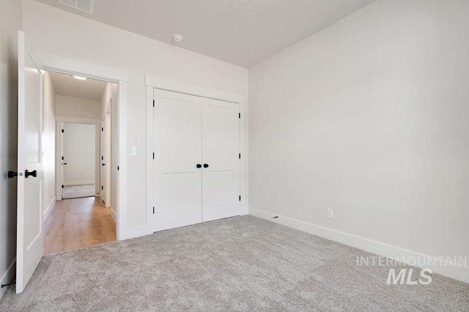 Unfurnished bedroom with light carpet and a closet