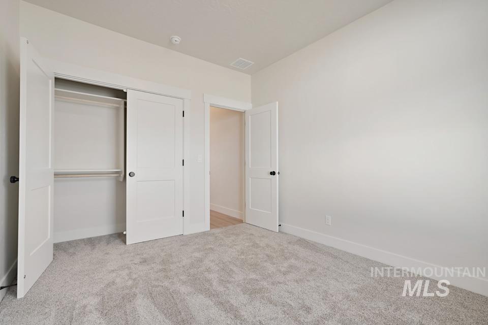 Unfurnished bedroom featuring light colored carpet and a closet