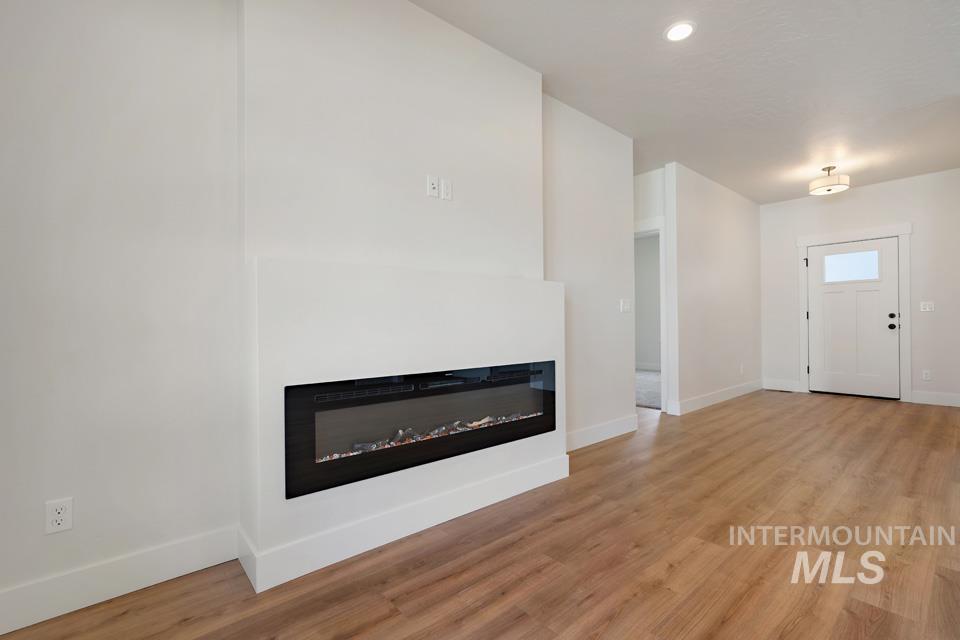 Unfurnished living room featuring a glass covered fireplace, light wood-style floors, and recessed lighting