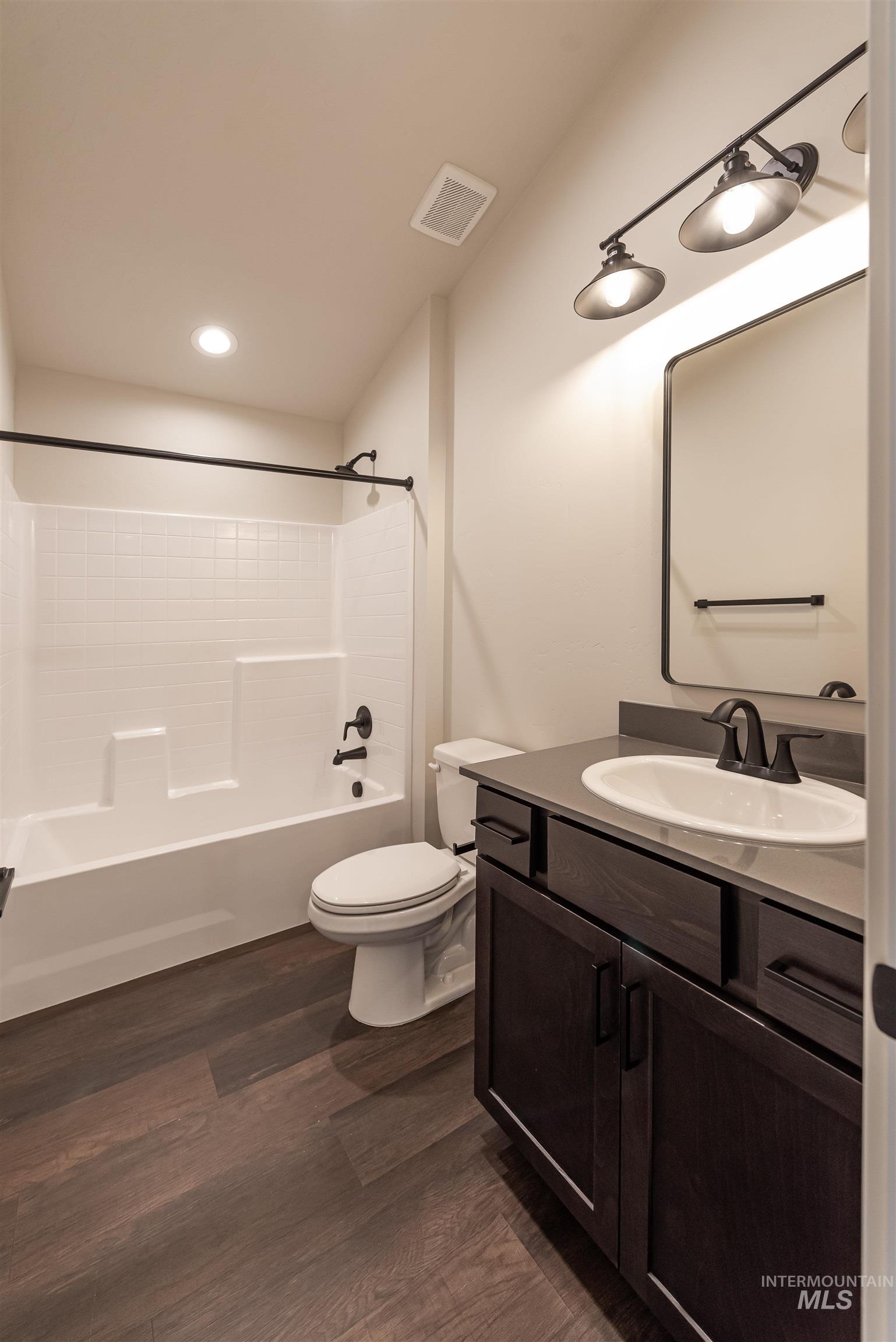 Bathroom with vanity, shower / tub combination, dark wood finished floors, and recessed lighting