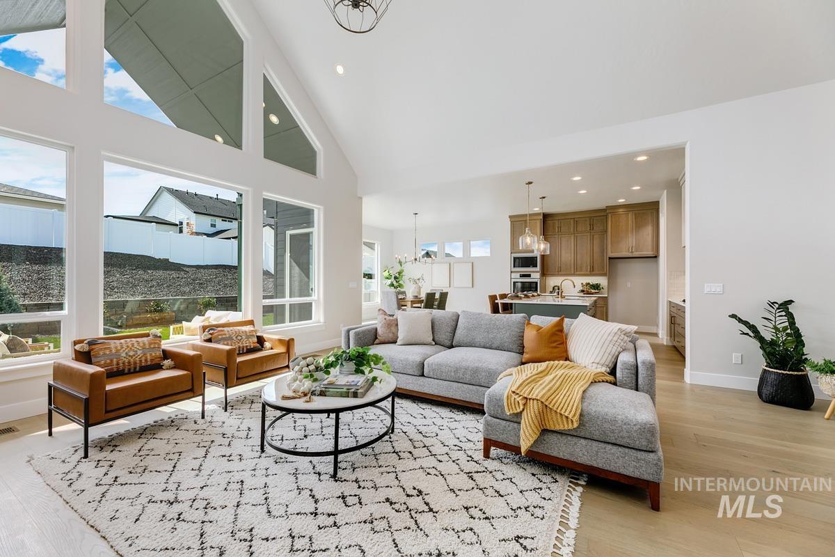 Living area featuring a chandelier, high vaulted ceiling, light wood-type flooring, and recessed lighting