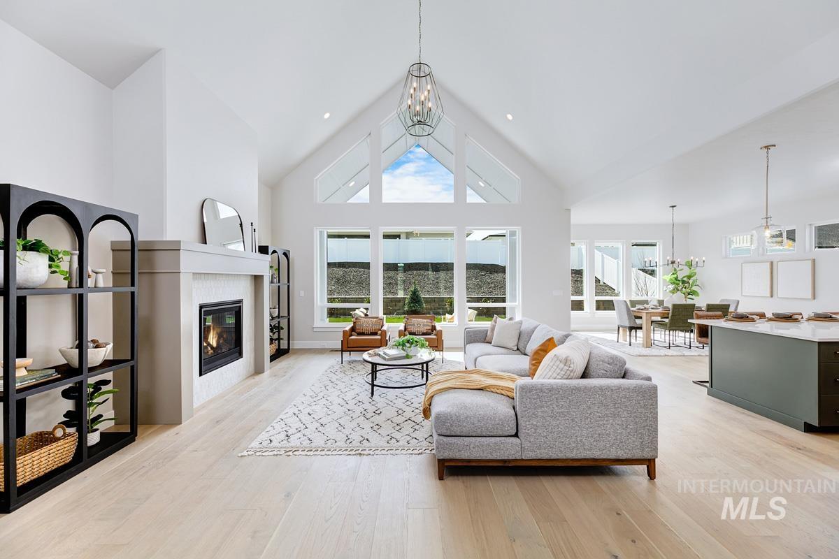 Living room featuring high vaulted ceiling, a chandelier, light wood-style floors, and a tile fireplace