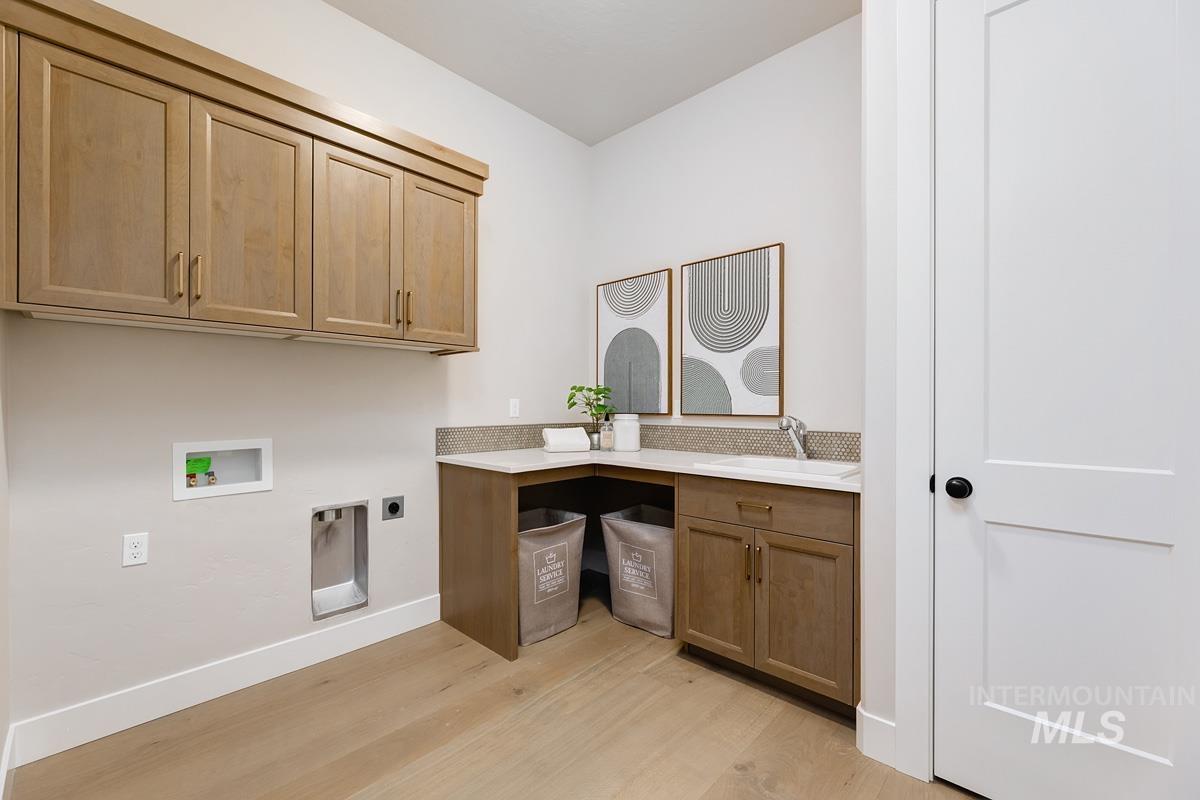 Laundry area featuring cabinet space, hookup for an electric dryer, hookup for a washing machine, and light wood-style flooring