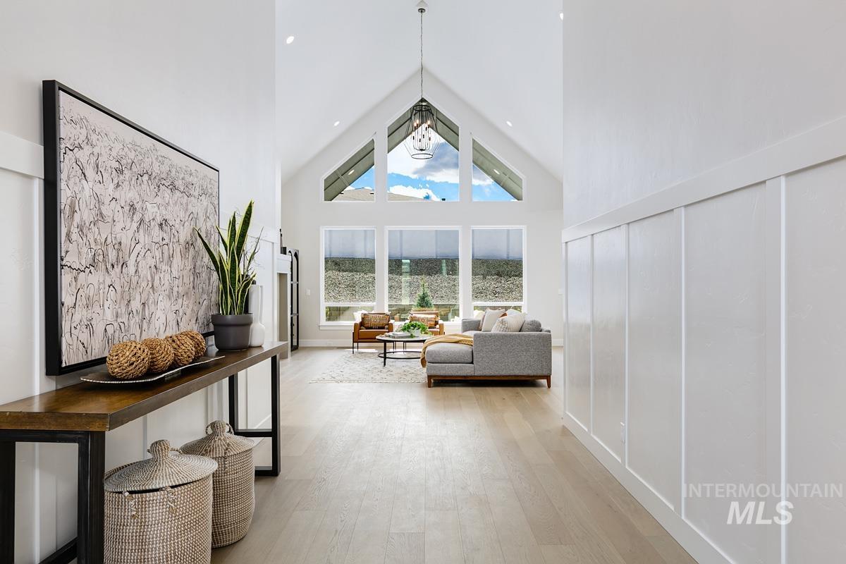Sitting room with high vaulted ceiling and light wood-style floors