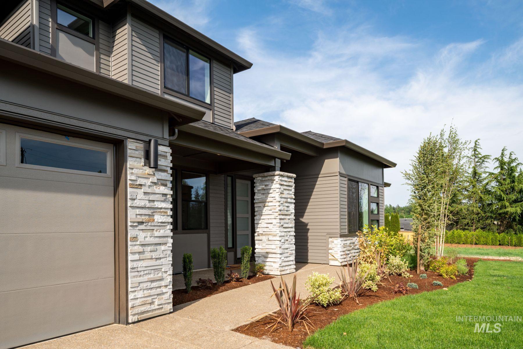 View of exterior entry with stone siding, a garage, and a yard