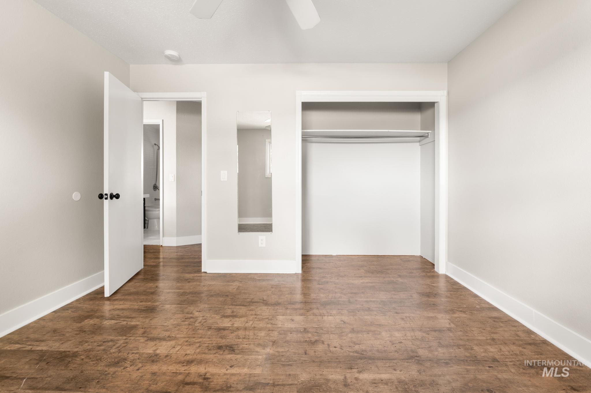 Unfurnished bedroom with dark wood-type flooring, ceiling fan, and a closet