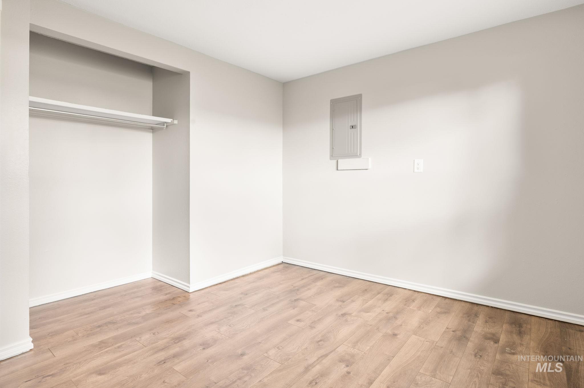 Unfurnished bedroom with light wood-style flooring, a closet, and electric panel