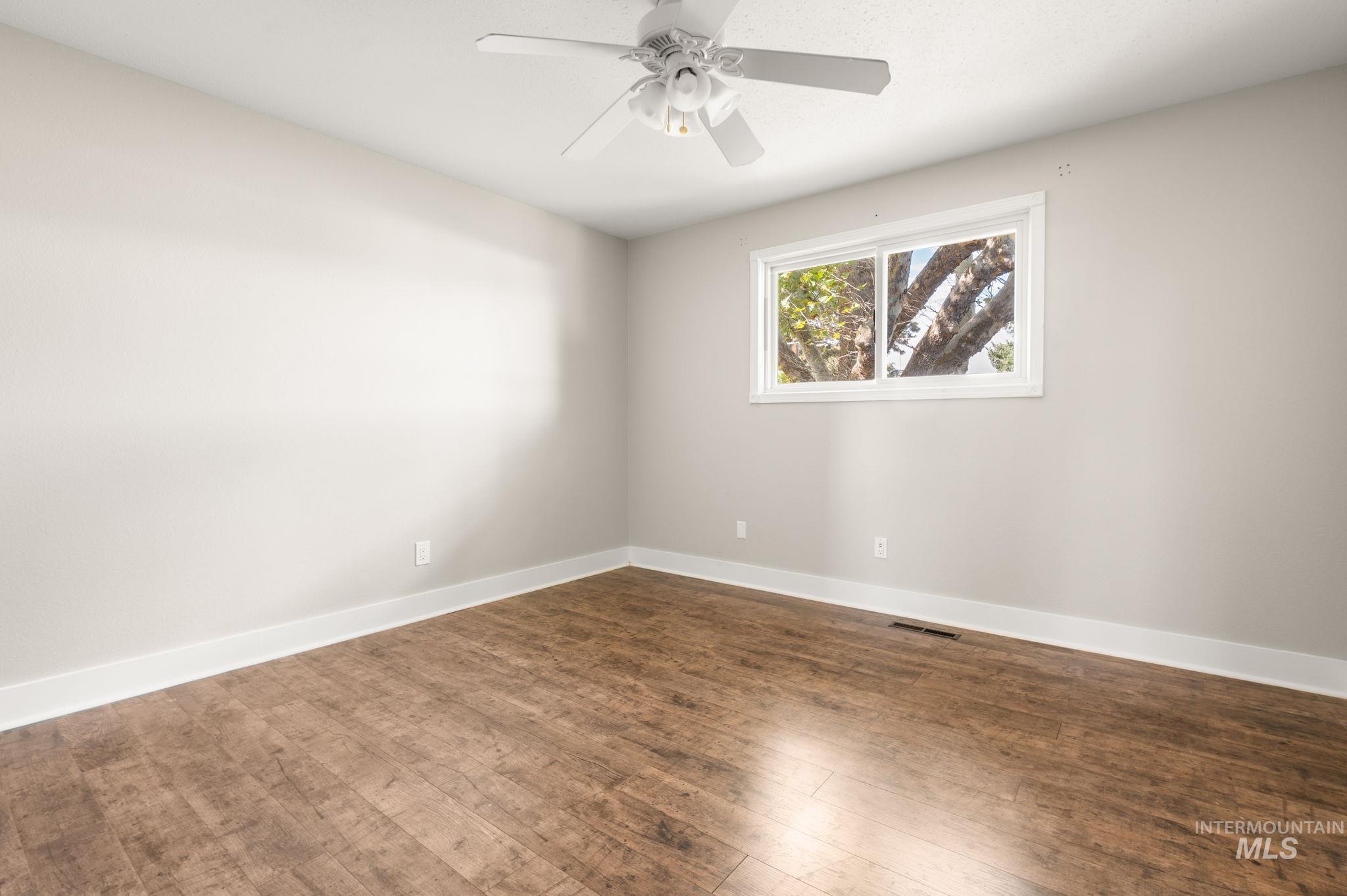 Spare room featuring dark wood finished floors and ceiling fan