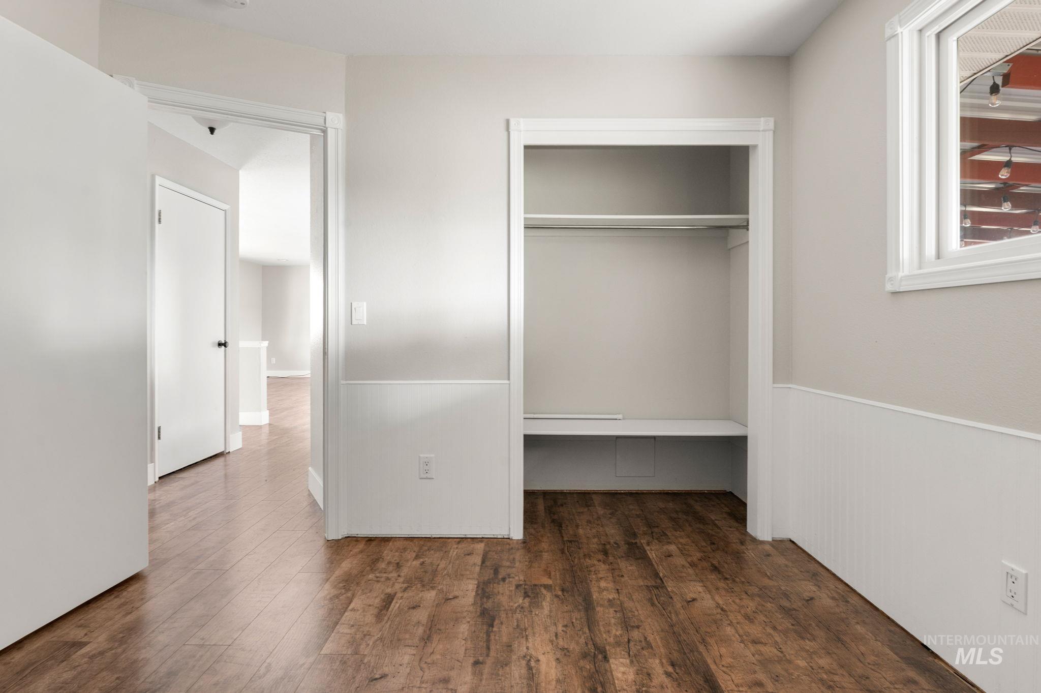 Unfurnished bedroom featuring dark wood-style flooring, built in desk, and a closet