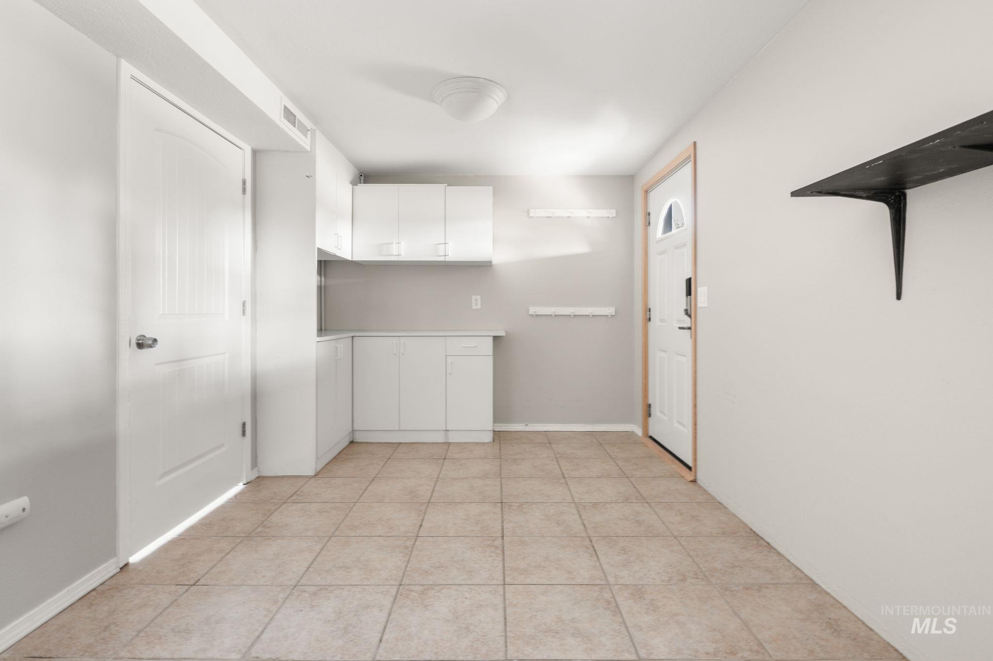 Kitchen featuring white cabinets, light countertops, and light tile patterned flooring