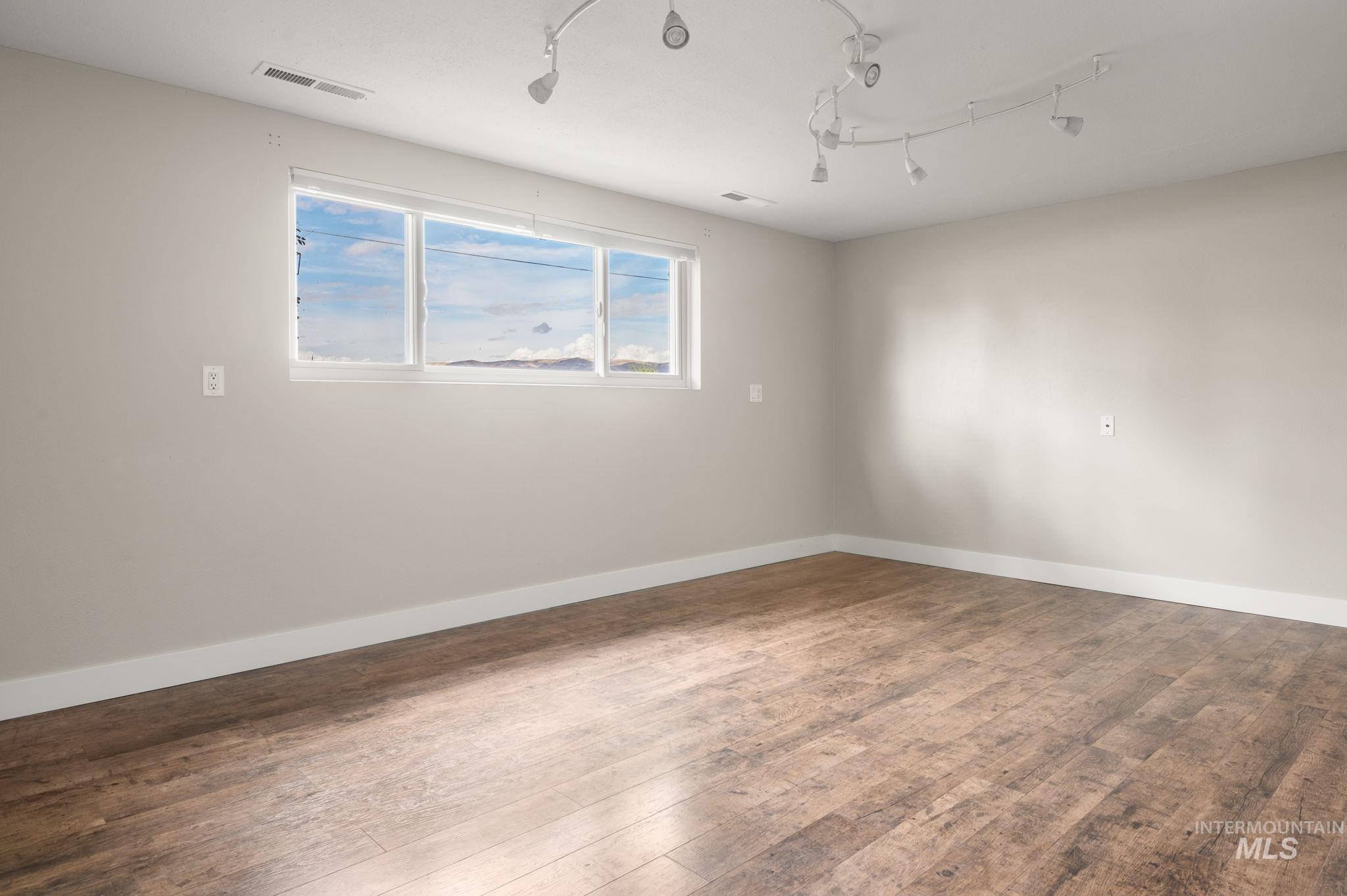 Spare room with wood finished floors and rail lighting