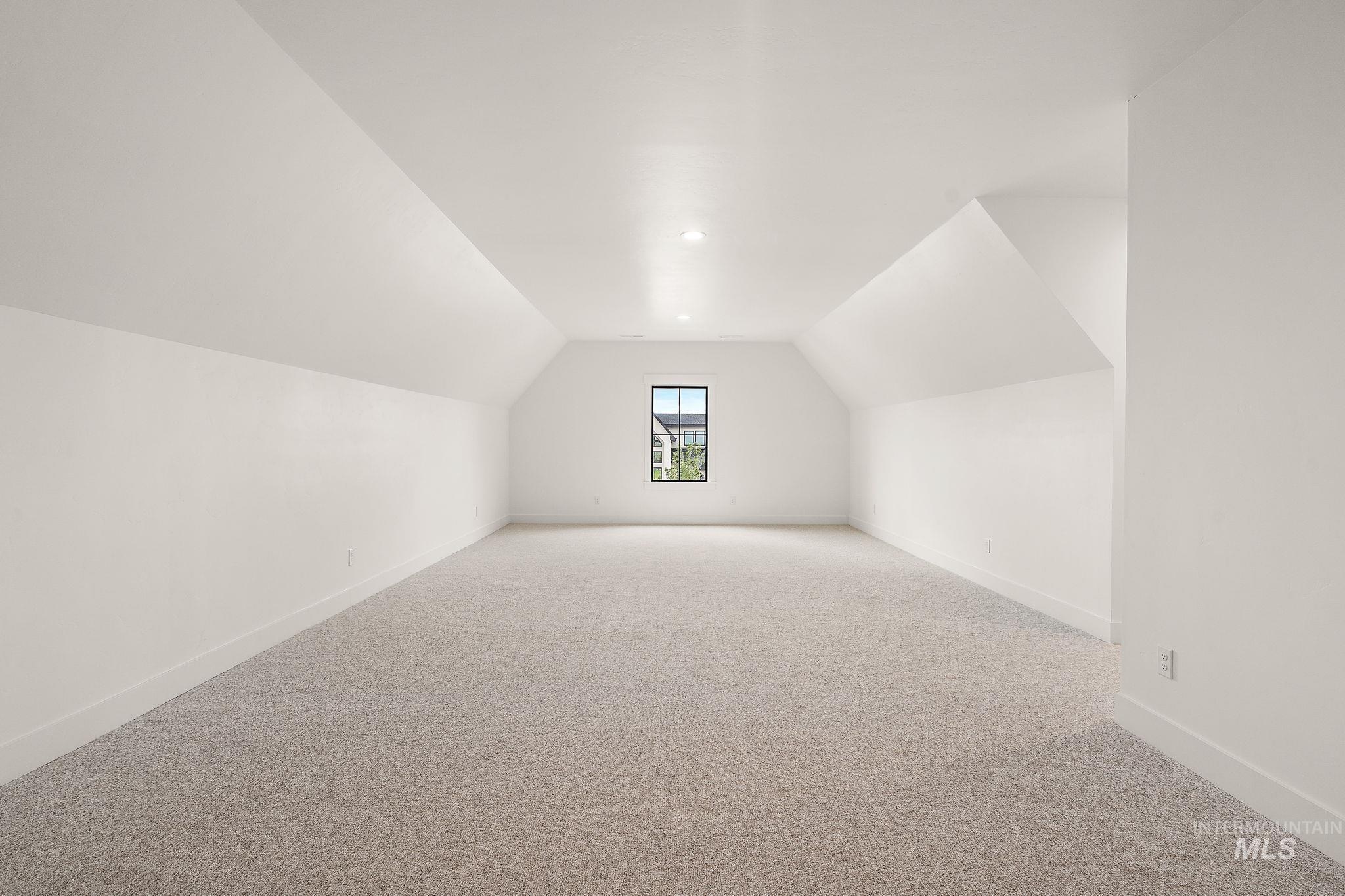 Additional living space with vaulted ceiling and light carpet