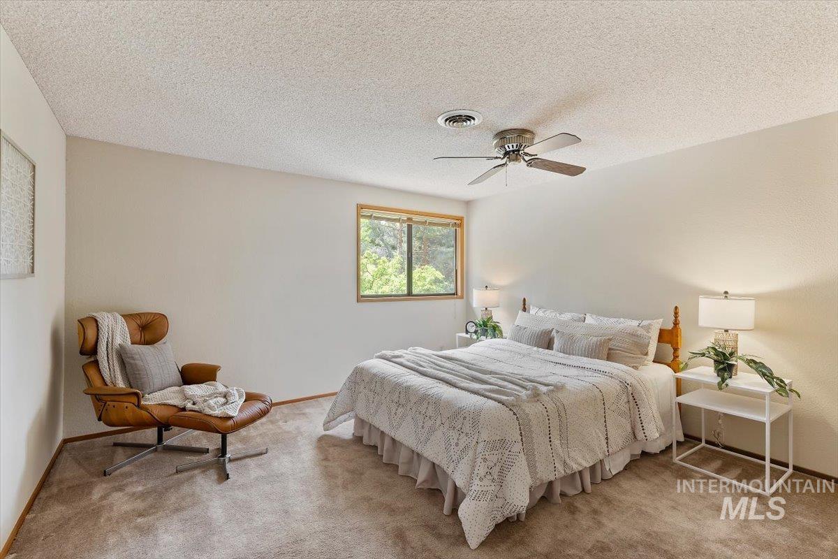 Bright room featuring a window with wood trim, neutral wall paint, and textured carpeting