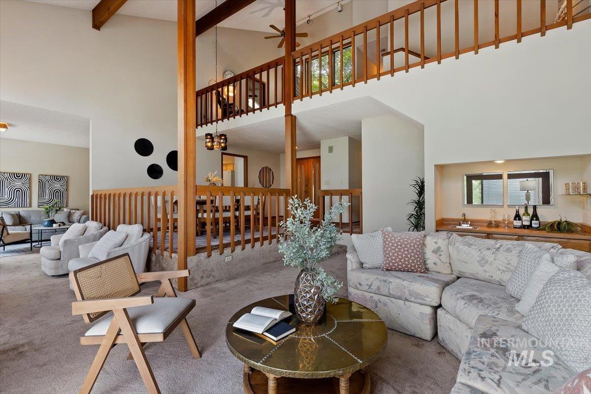 Vaulted ceiling living area featuring an open balcony, exposed wood beams, and a built-in wet bar