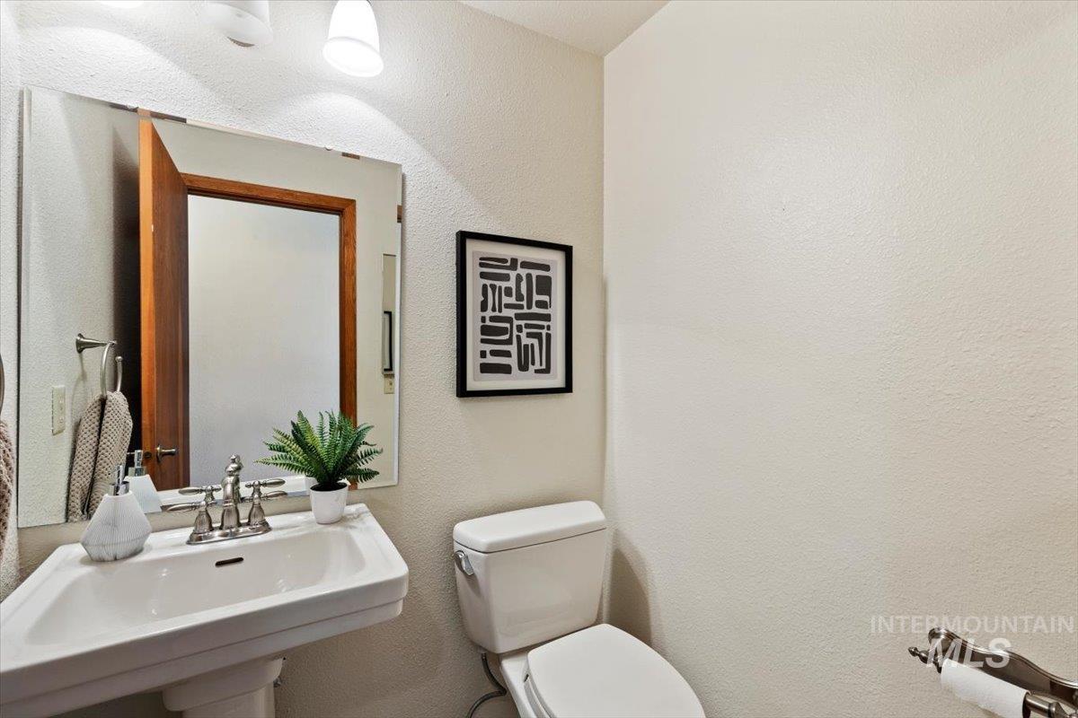 Pedestal sink with chrome faucet, framed mirror, and white toilet