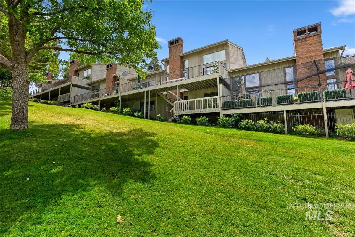 Terraced multi-story property with multiple private decks, brick chimney features, and an expansive sloped lawn