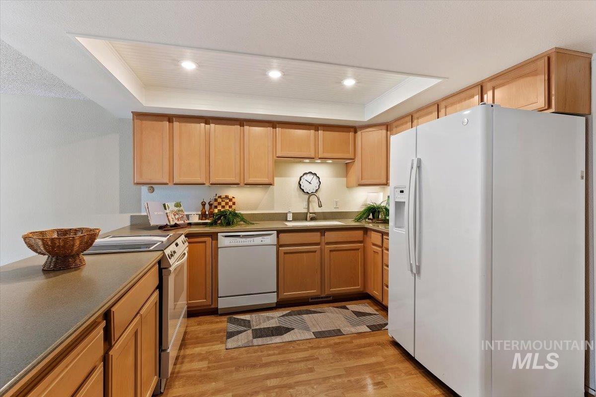 Kitchen featuring wood-finish flooring, recessed ceiling lighting, light wood cabinetry, and a neutral countertop