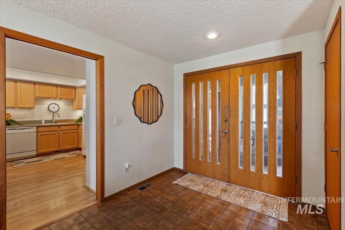 Entryway featuring dual wood doors with vertical glass inserts, recessed lighting, and tile flooring