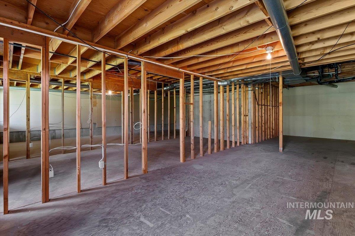 Expansive unfinished basement featuring visible wood framing, concrete flooring, exposed ceiling joists, and foundational walls