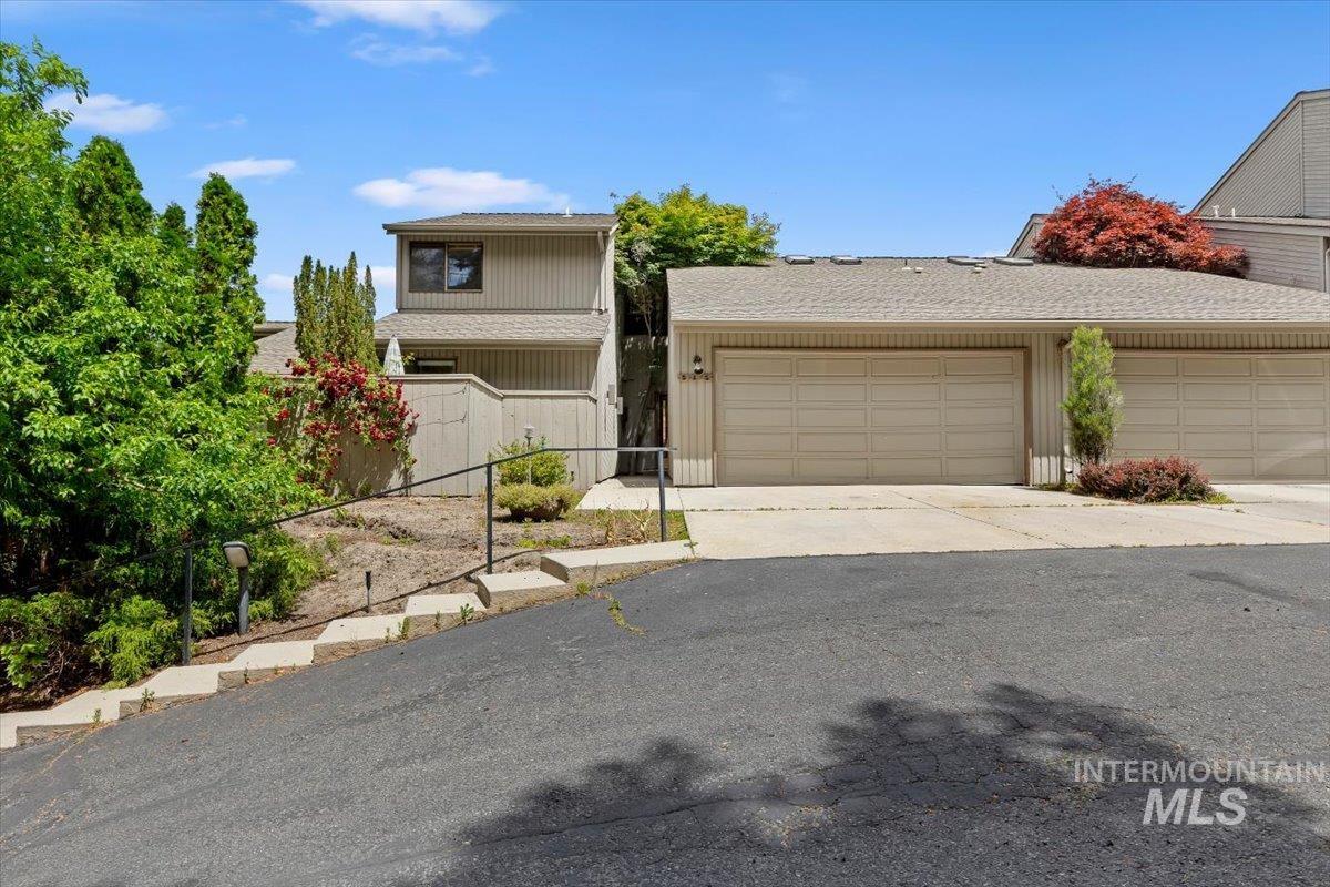 Exterior featuring muted siding, a two-car garage with panel doors, and a terraced walkway with handrail