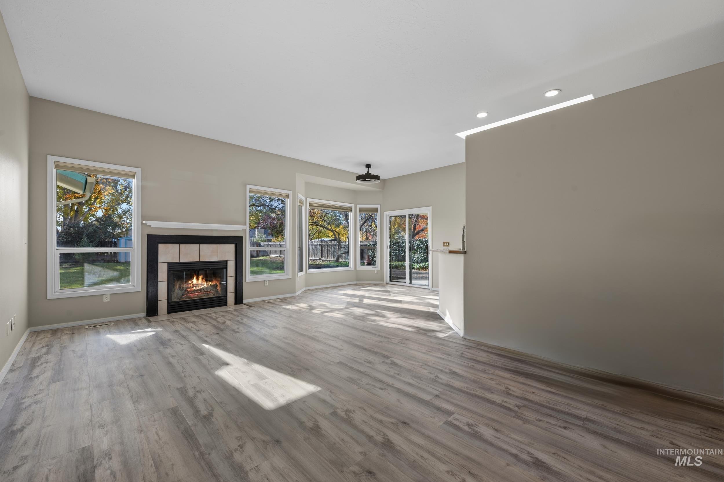 Unfurnished living room with recessed lighting, a tiled fireplace, and wood finished floors