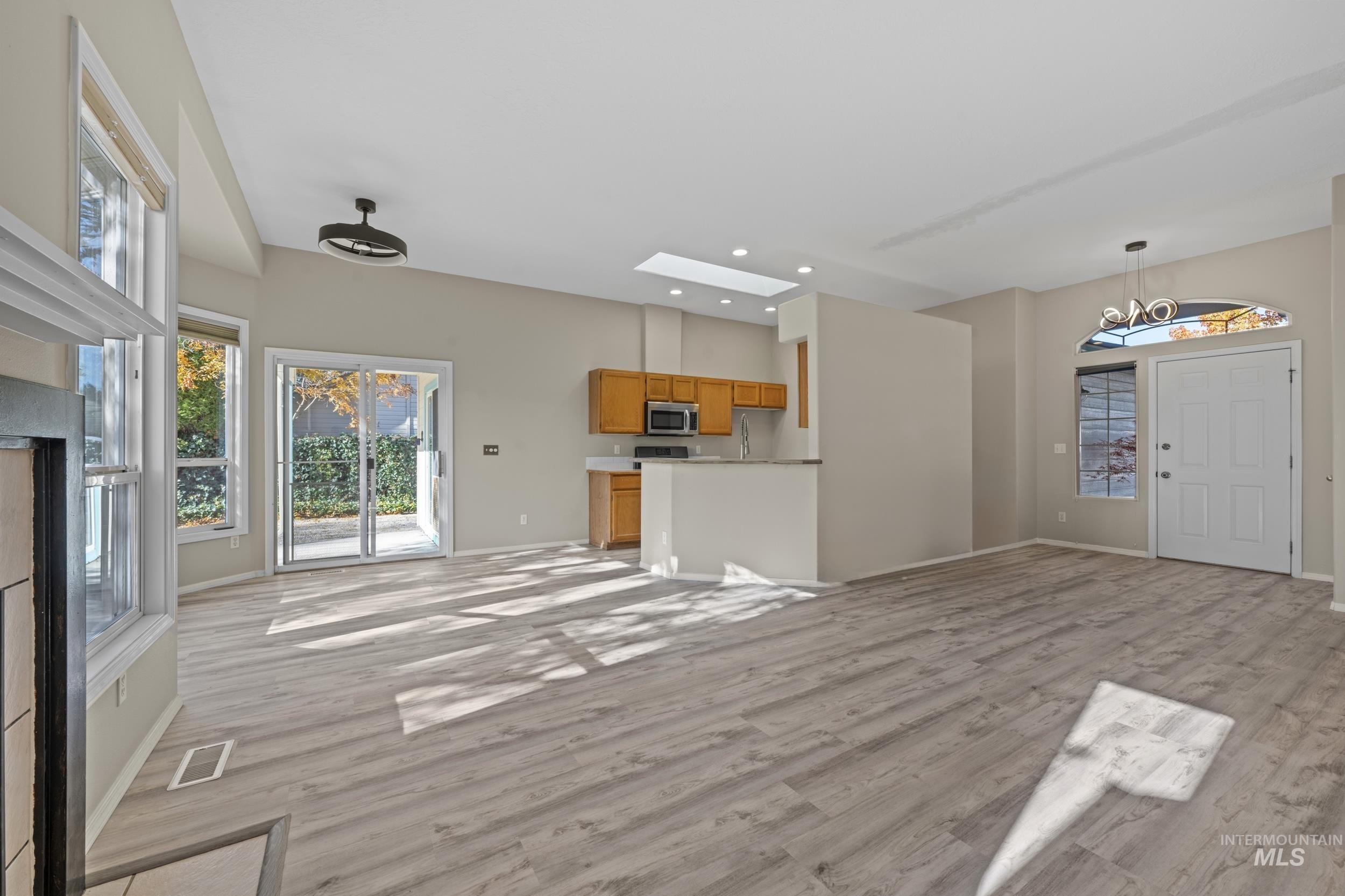 Unfurnished living room featuring light wood-style flooring, a skylight, and recessed lighting