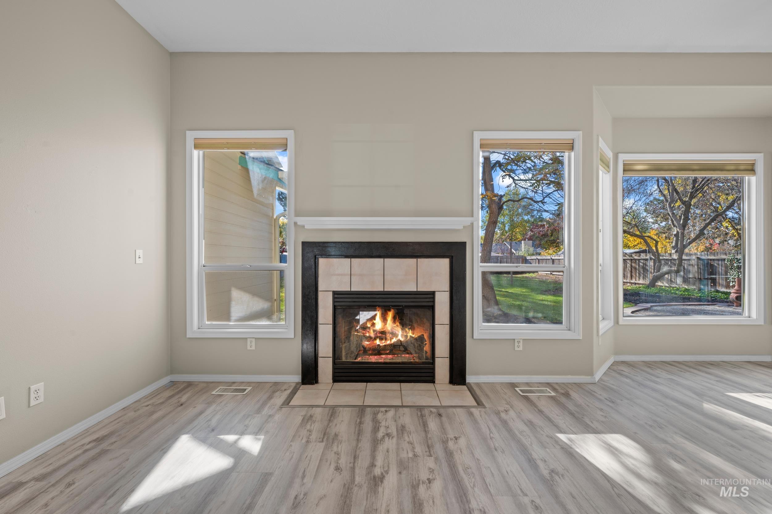 Unfurnished living room featuring a tile fireplace and wood finished floors