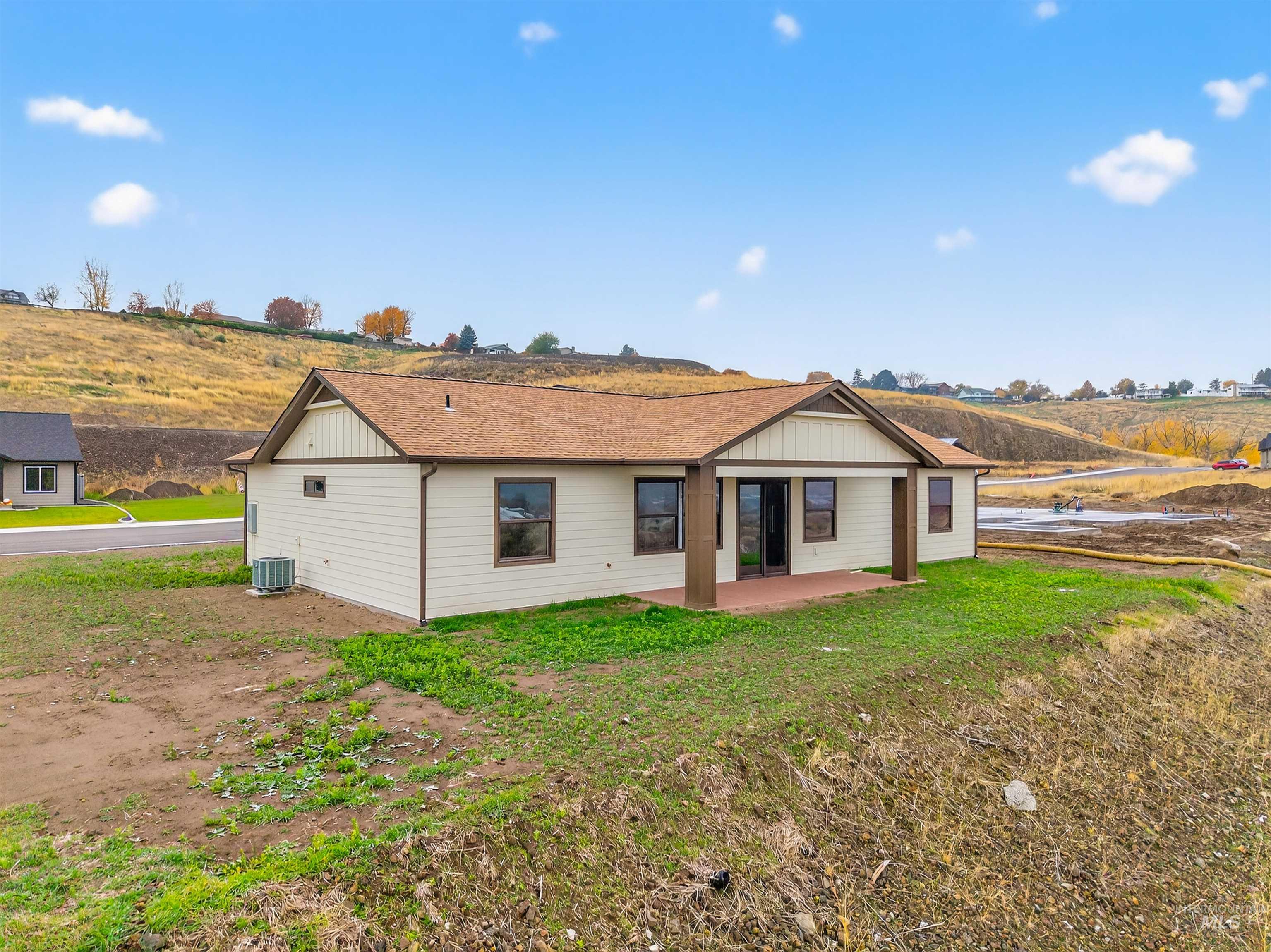 View of front of house with a patio area, a front lawn, and a shingled roof