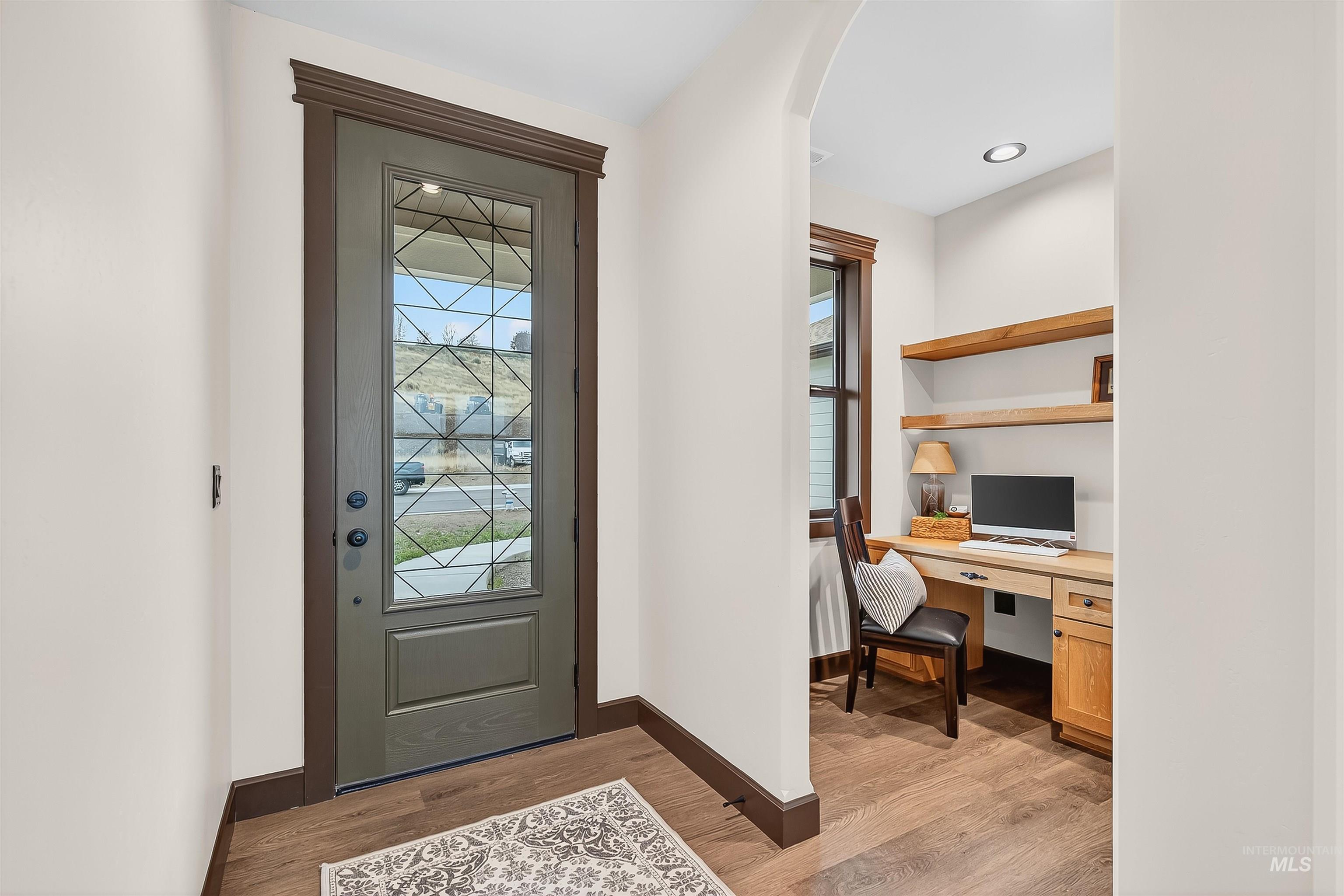 Foyer entrance featuring healthy amount of natural light, light wood-style floors, built in study area, and arched walkways