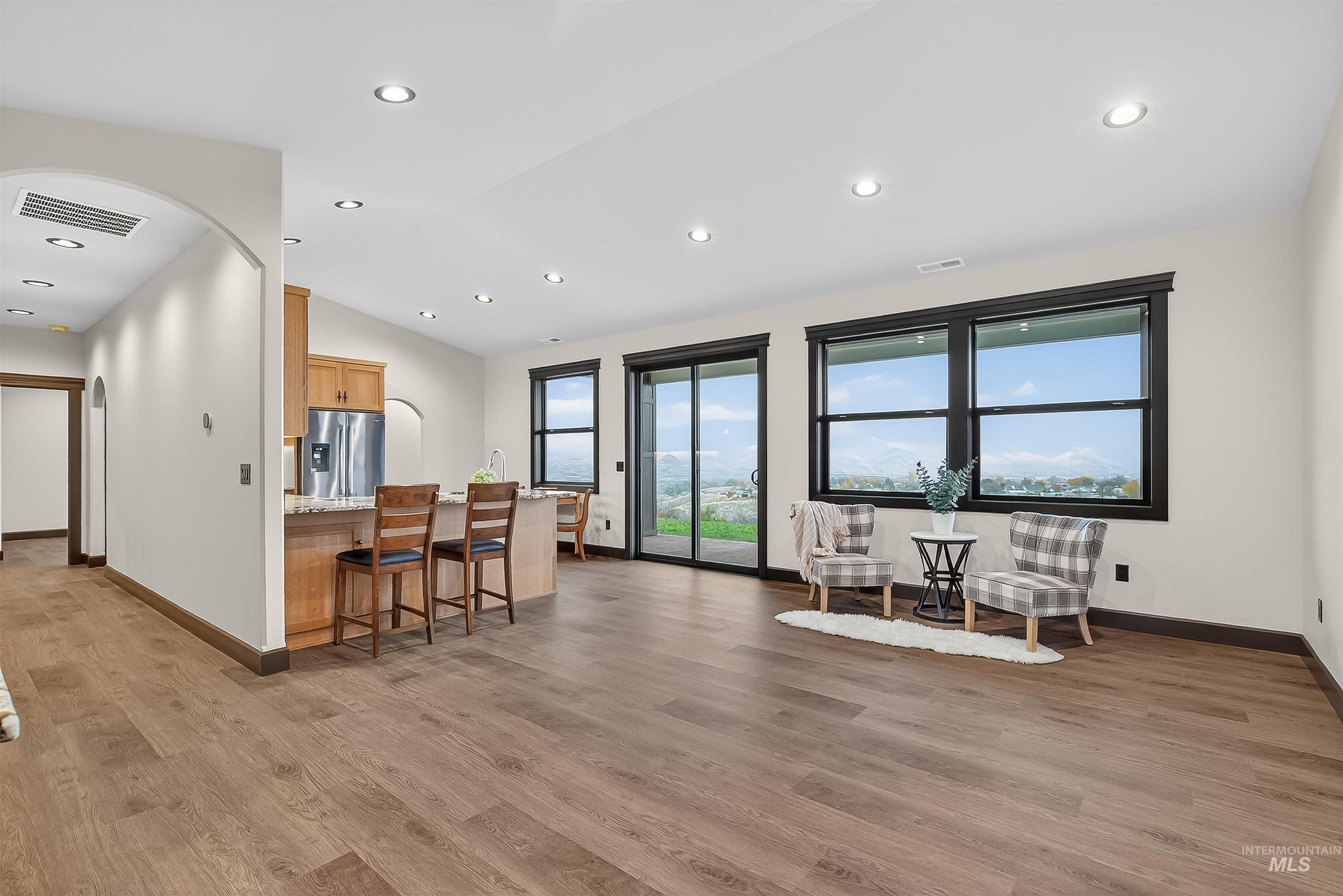 Kitchen with a breakfast bar area, arched walkways, light wood finished floors, recessed lighting, and lofted ceiling